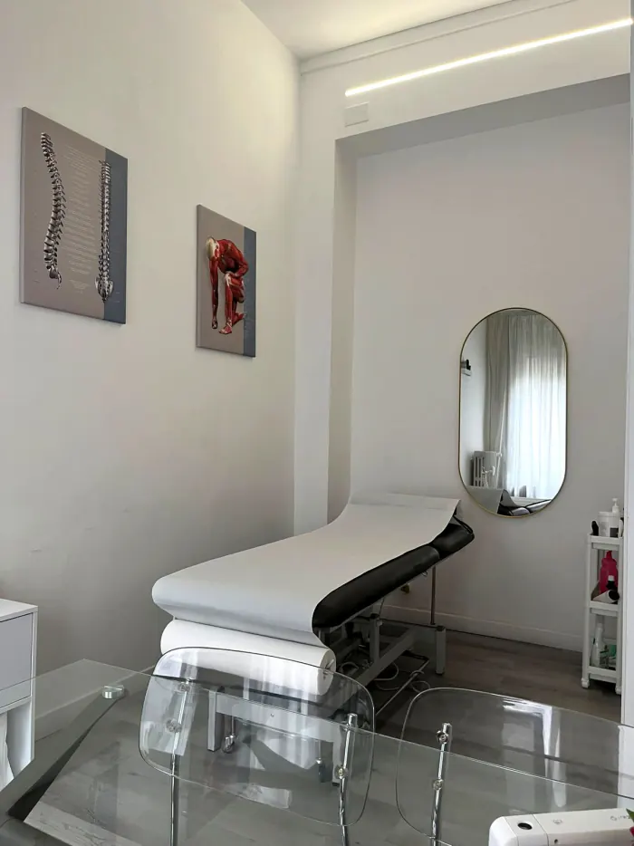 Lettino da visita bianco con specchio e quadri anatomici