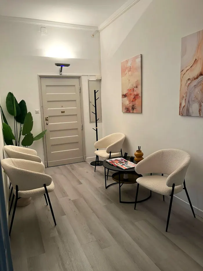 Sala d'attesa luminosa con poltroncine bianche e una pianta