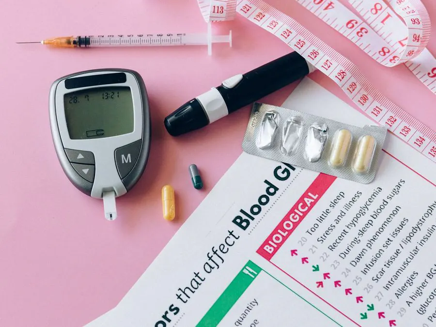 Glucometro, pungidito e tabella dei fattori che influenzano la glicemia su fondo rosa